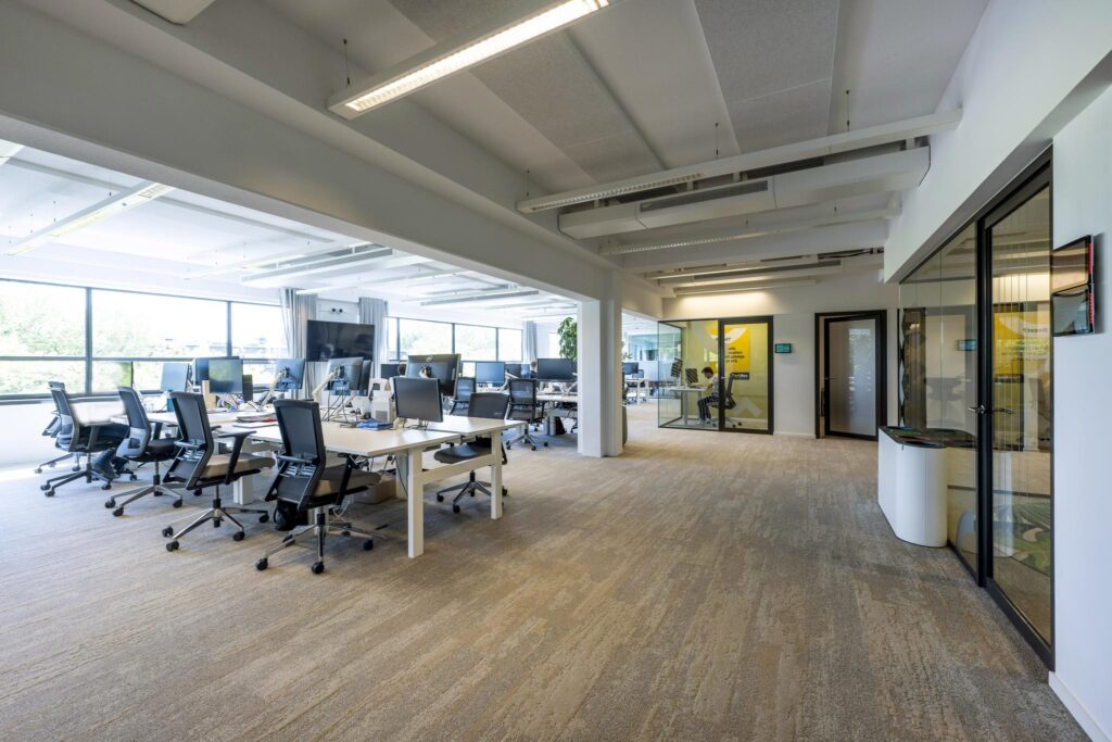 Modern open-plan office space on Mr. Treublaan with workstations, large windows, and glass-walled meeting rooms.